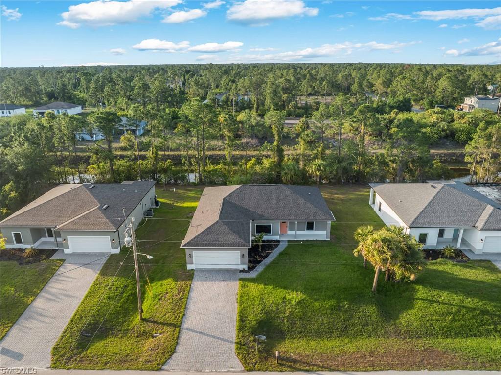 Aerial view of property and surrounding area featuring a forest