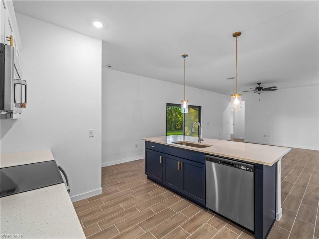 Kitchen featuring stainless steel appliances, a sink, blue cabinets, wood finish floors, and recessed lighting