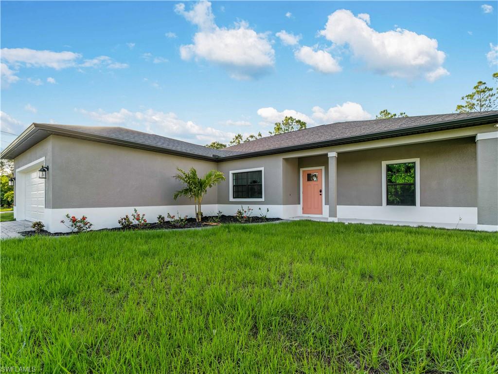 Ranch-style house with stucco siding, an attached garage, and a front yard