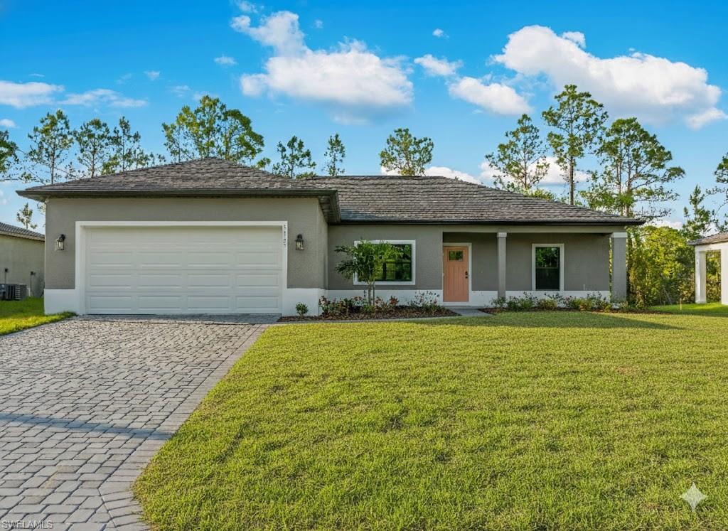 Ranch-style house featuring stucco siding, a front yard, and decorative driveway