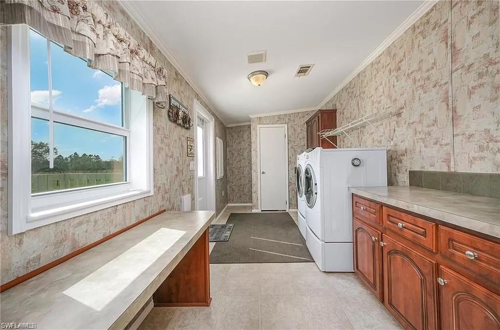 Laundry area with washer and dryer, cabinets, ornamental molding, and light tile floors