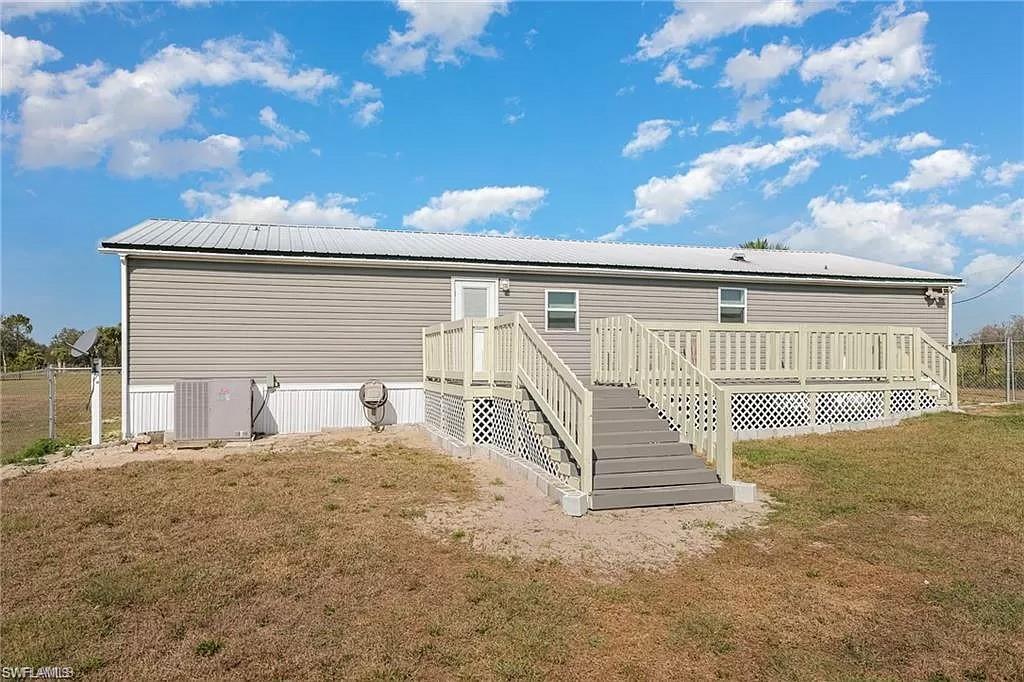 Rear view of house featuring a yard and a wooden deck