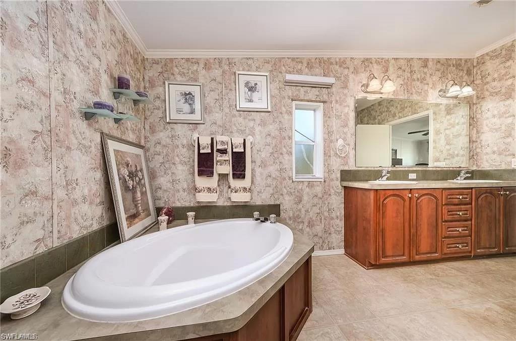 Bathroom featuring a relaxing tiled bath, tile flooring, dual bowl vanity, and crown molding