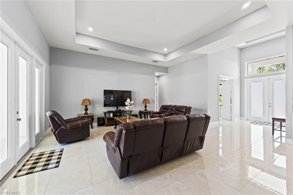 Tiled living room with a raised ceiling and french doors