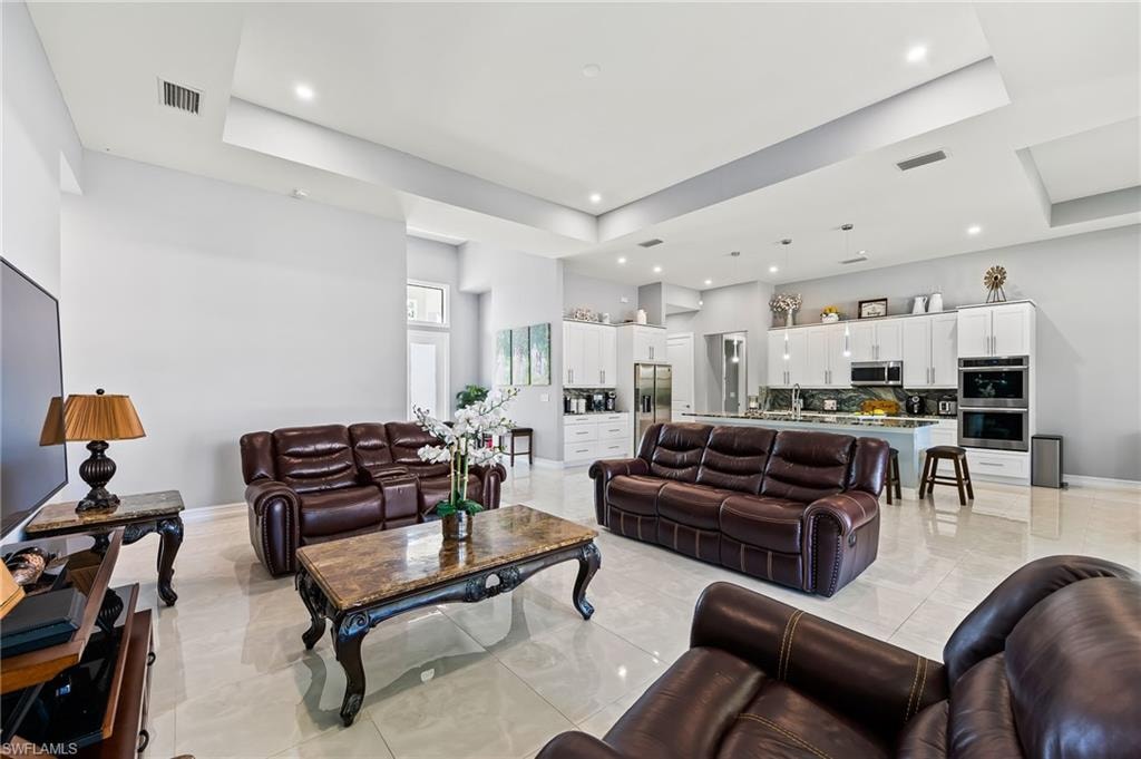 Living room featuring a tray ceiling and light tile floors