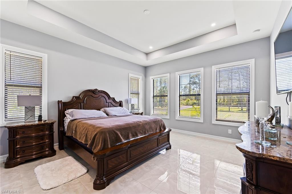 Bedroom with a raised ceiling and light tile flooring