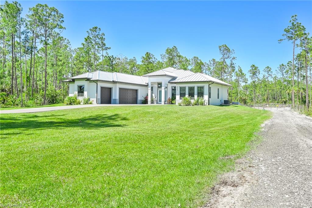 View of front of home featuring a front yard, a garage, and central AC unit