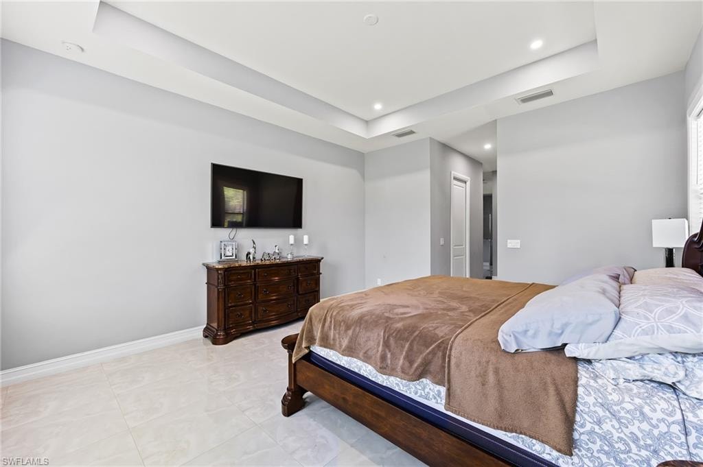 Bedroom featuring a tray ceiling and light tile flooring