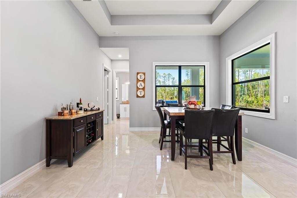 Dining room with light tile flooring and a raised ceiling