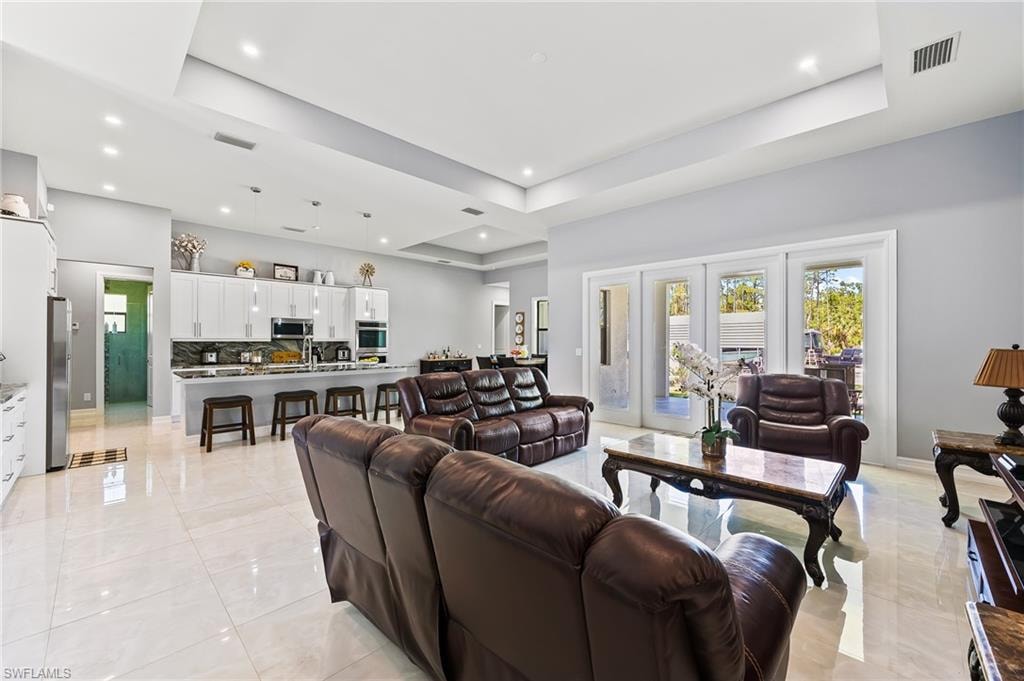Living room with a tray ceiling and light tile floors