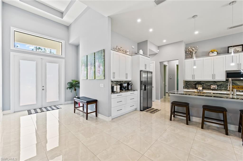 Kitchen with appliances with stainless steel finishes, backsplash, dark stone countertops, and a kitchen bar