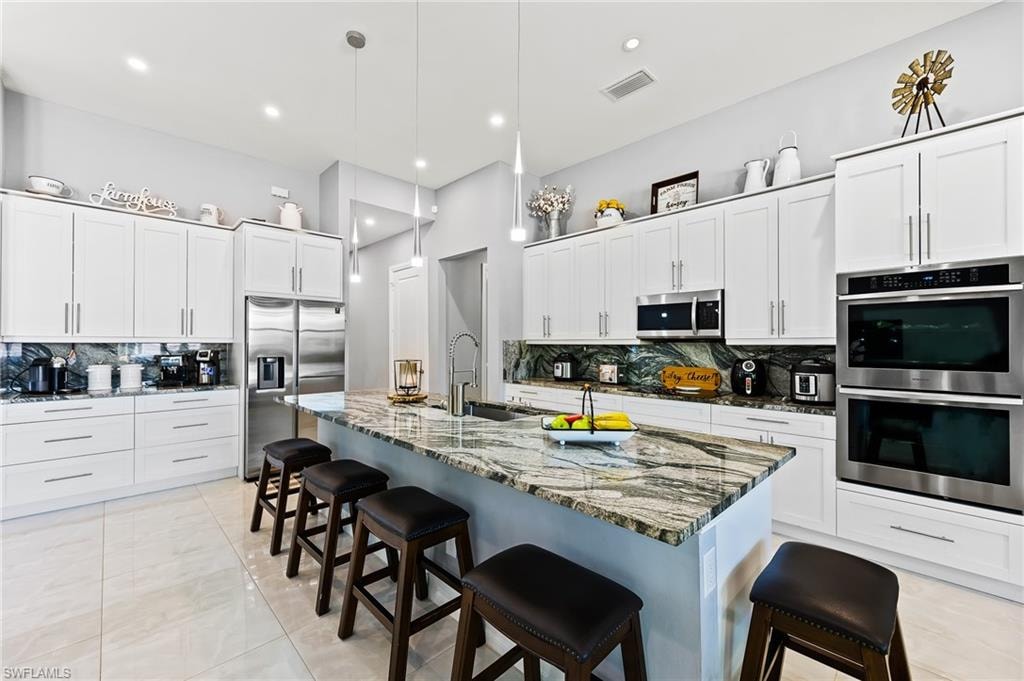 Kitchen with appliances with stainless steel finishes, a kitchen breakfast bar, and backsplash