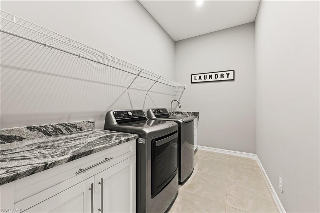 Laundry room with washer and clothes dryer, cabinets, and light tile floors