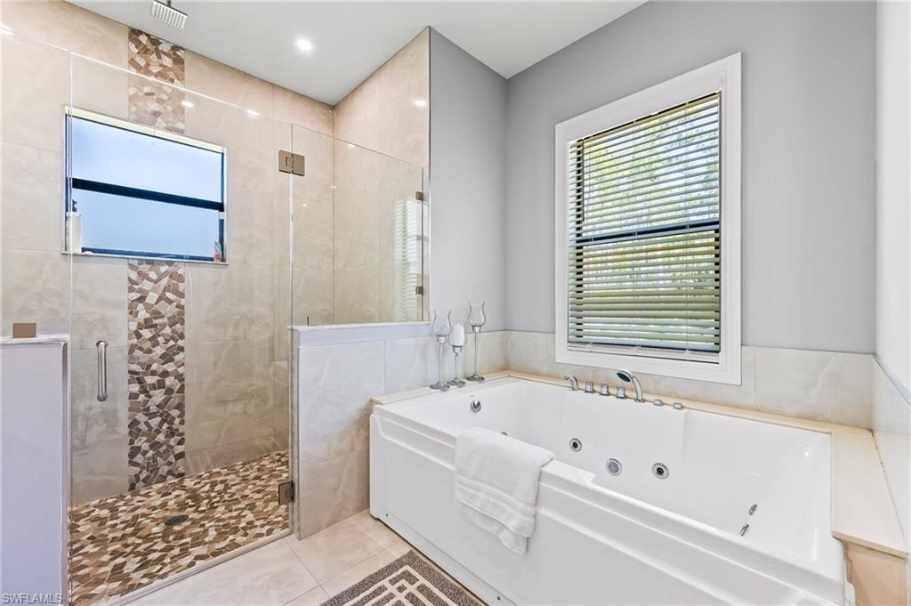 Bathroom featuring tile flooring, tile walls, and plus walk in shower