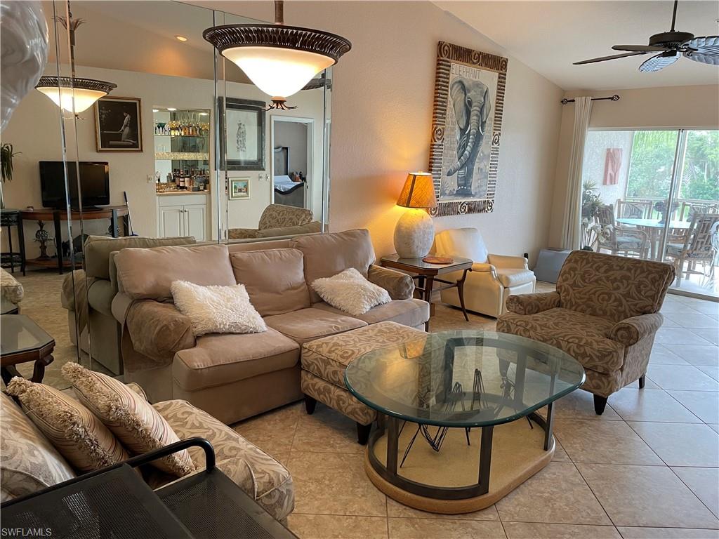 Tiled living room with ceiling fan and vaulted ceiling
