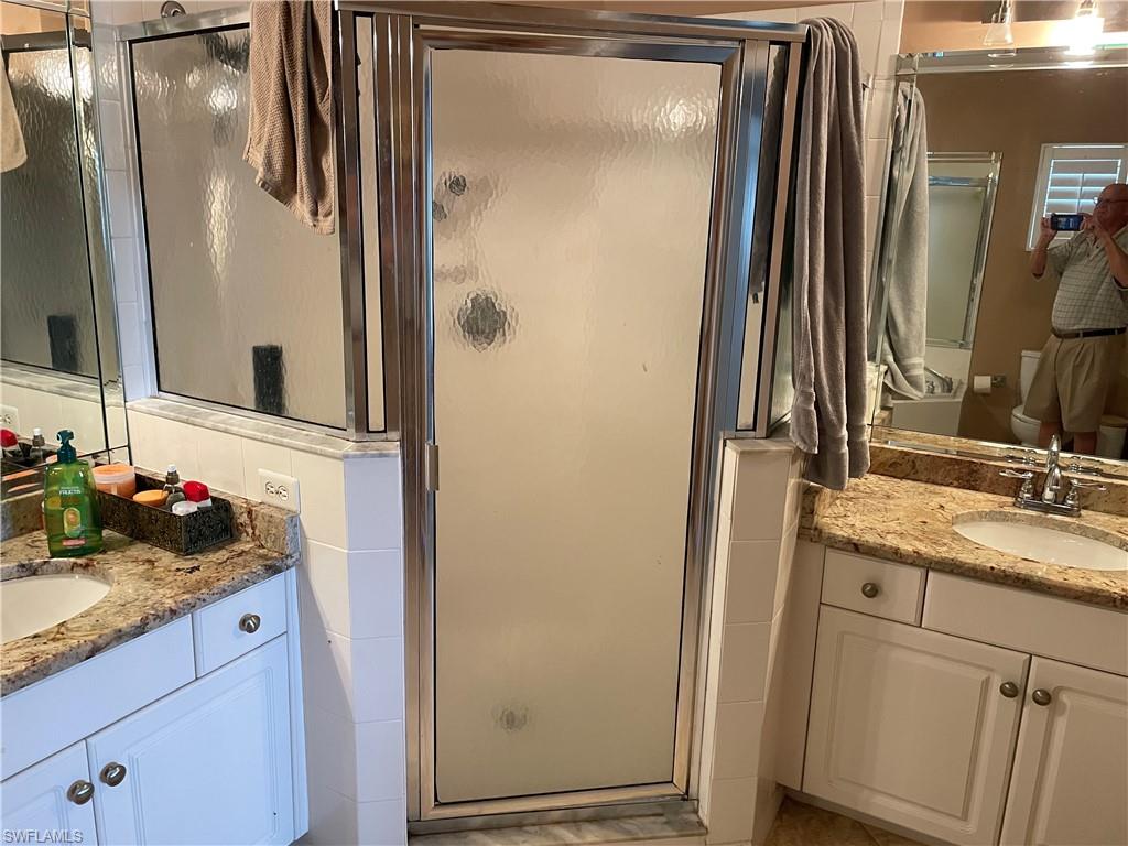 Bathroom with a shower with door, tasteful backsplash, and large vanity
