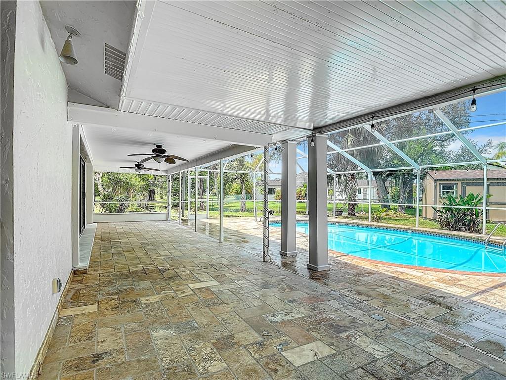 View of pool featuring a patio, glass enclosure, and ceiling fan