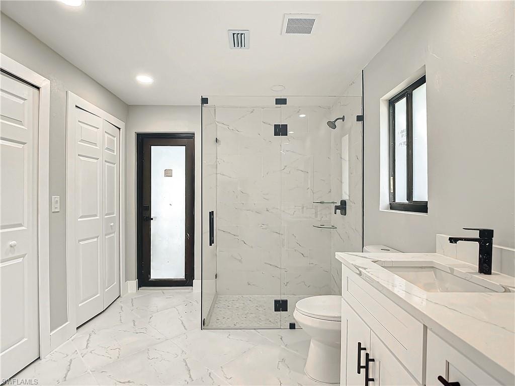 Bathroom with a shower with shower door, vanity, toilet, and tile floors