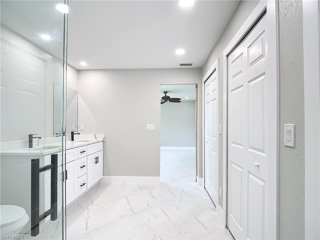 Bathroom with tile floors, ceiling fan, double vanity, and toilet