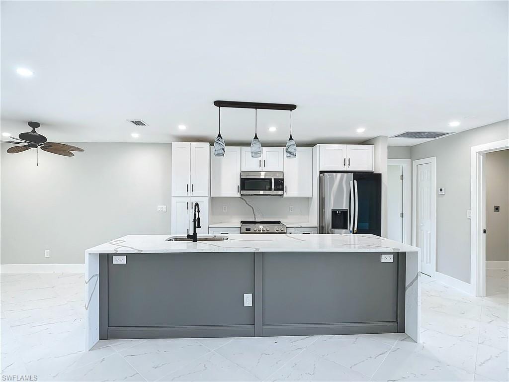 Kitchen featuring a center island with sink, appliances with stainless steel finishes, and light tile floors