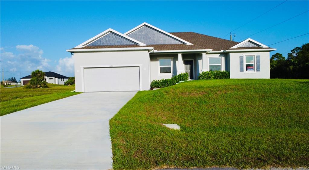 Ranch-style house featuring stucco siding, an attached garage, driveway, and a front lawn