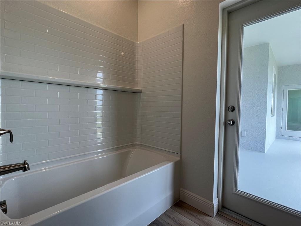 Bathroom featuring wood finished floors and tub / shower combination