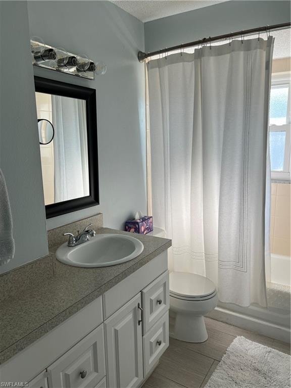 Full bathroom with shower / bath combo with shower curtain, a textured ceiling, vanity, and toilet