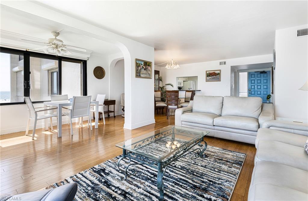 Living room featuring ceiling fan with notable chandelier and hardwood / wood-style floors