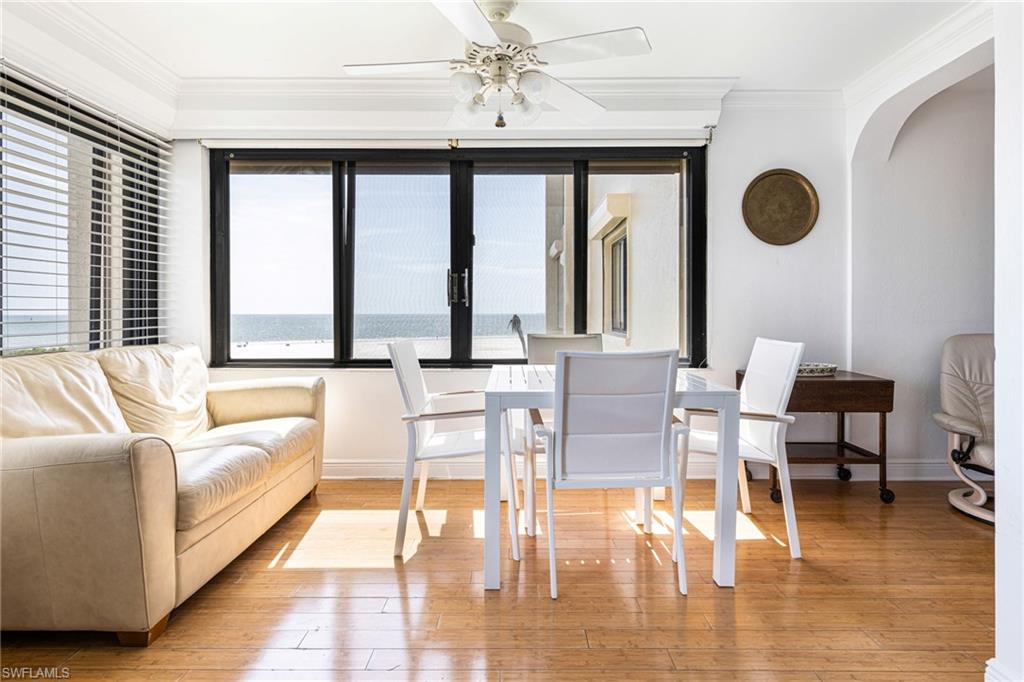 Dining space with light hardwood / wood-style flooring, ornamental molding, a water view, and ceiling fan
