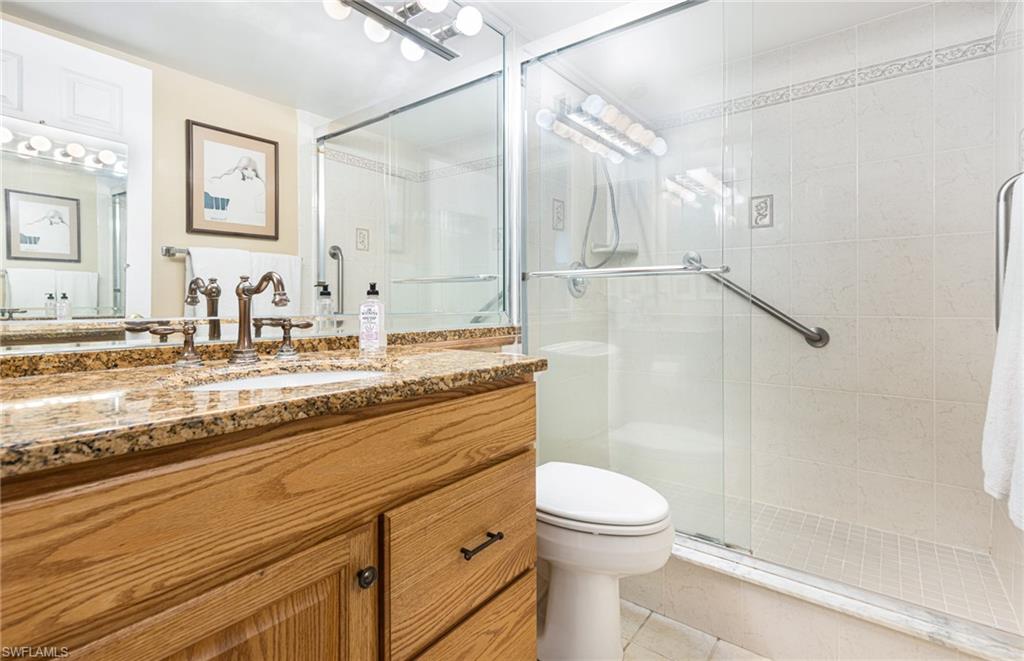 Bathroom featuring walk in shower, vanity, tile patterned flooring, and toilet
