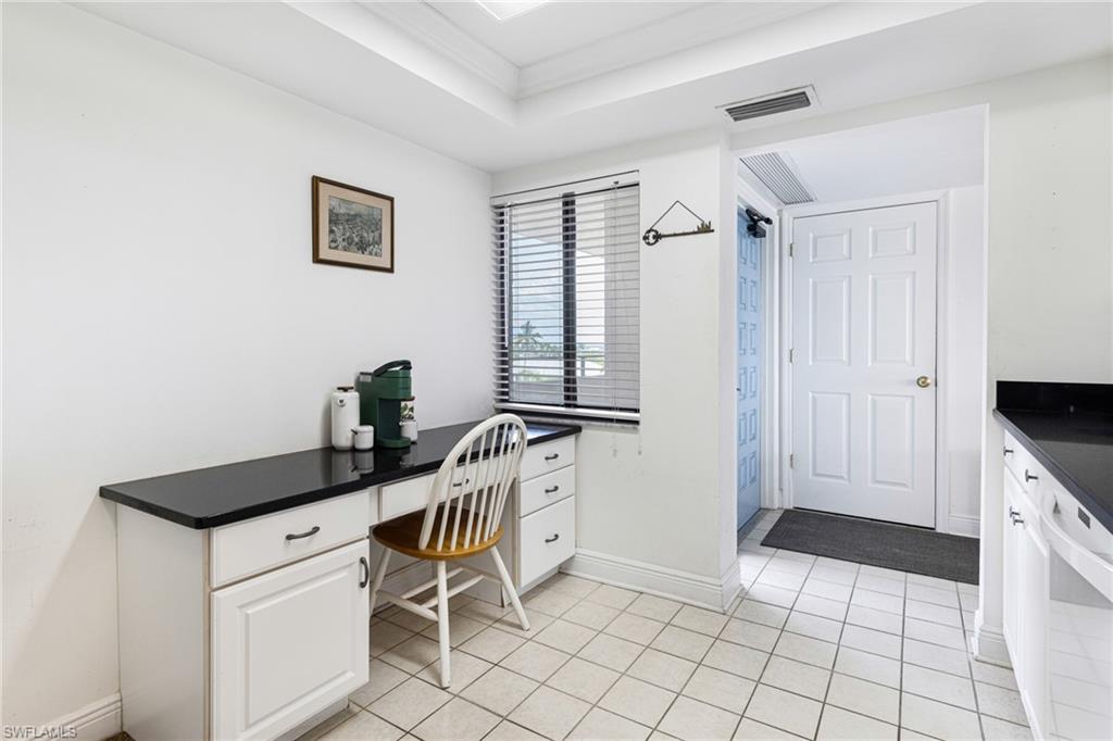 Office space with ornamental molding, light tile patterned floors, and a raised ceiling