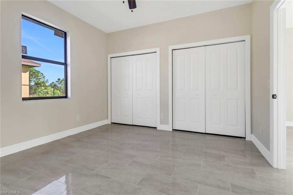Unfurnished bedroom featuring two closets, ceiling fan, and light tile patterned flooring