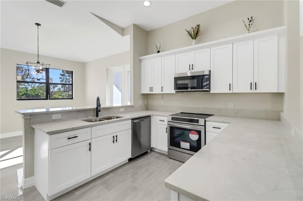 Kitchen with kitchen peninsula, pendant lighting, stainless steel appliances, and sink
