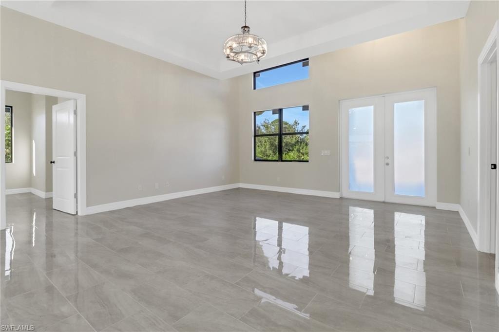 Spare room with french doors and a notable chandelier