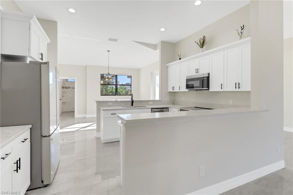 Kitchen featuring white cabinets, kitchen peninsula, sink, and appliances with stainless steel finishes
