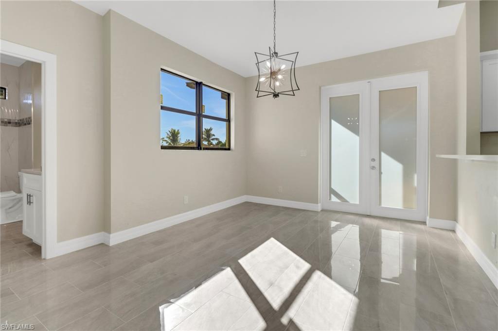 Spare room featuring an inviting chandelier and french doors