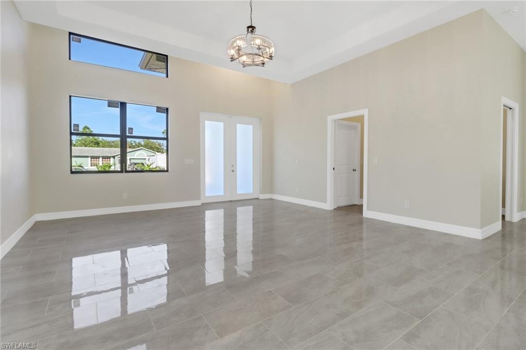 Spare room featuring a towering ceiling and a chandelier