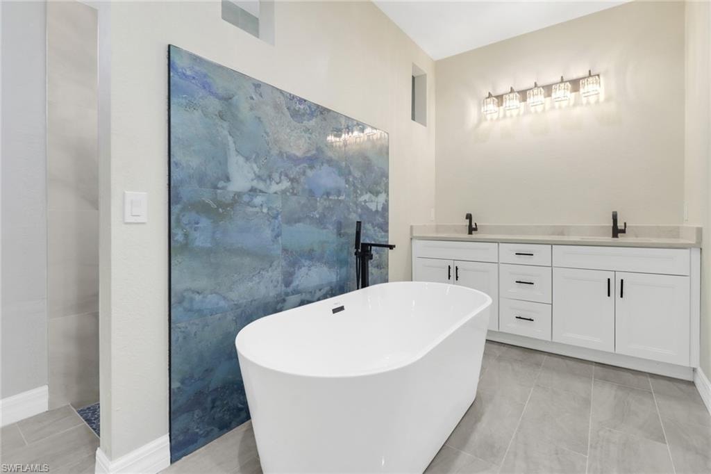 Bathroom with a washtub, vanity, tile patterned floors, and tile walls