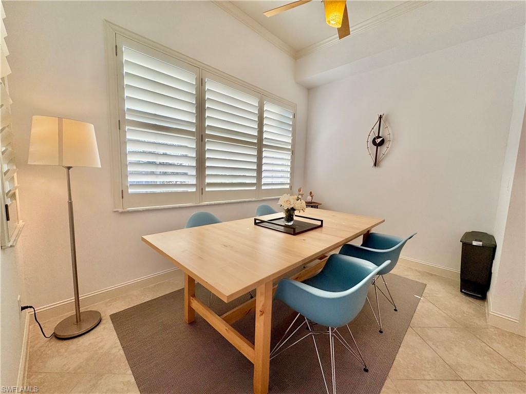 Tiled dining room with crown molding and ceiling fan