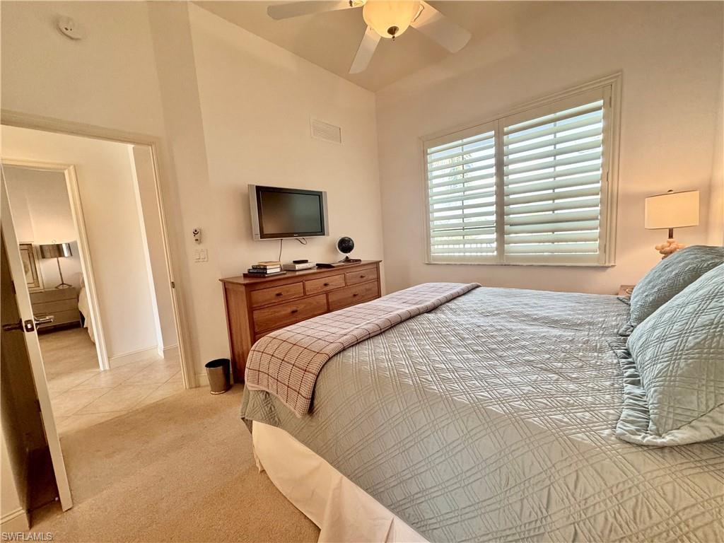 Guest bedroom with ceiling fan, light carpet, and attached guest bathroom