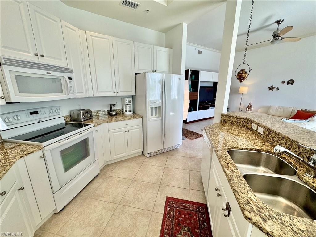 Kitchen with white appliances, white cabinets, sink, and light tile patterned floors
