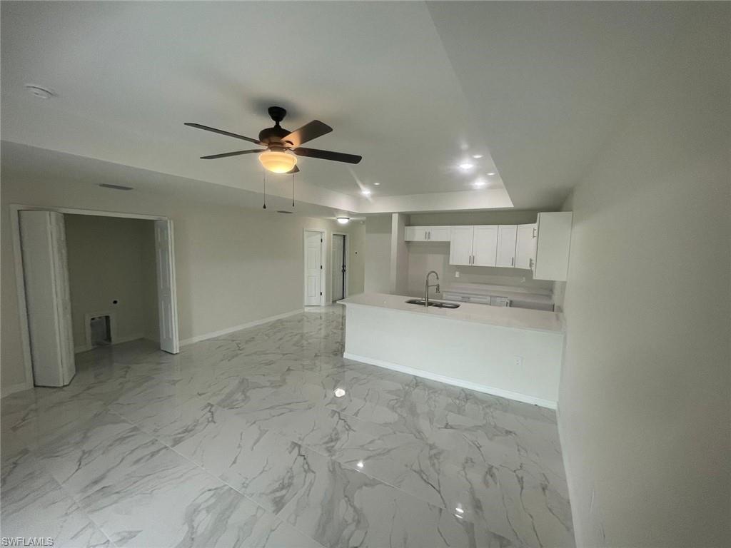 Kitchen featuring white cabinetry, kitchen peninsula, sink, and ceiling fan