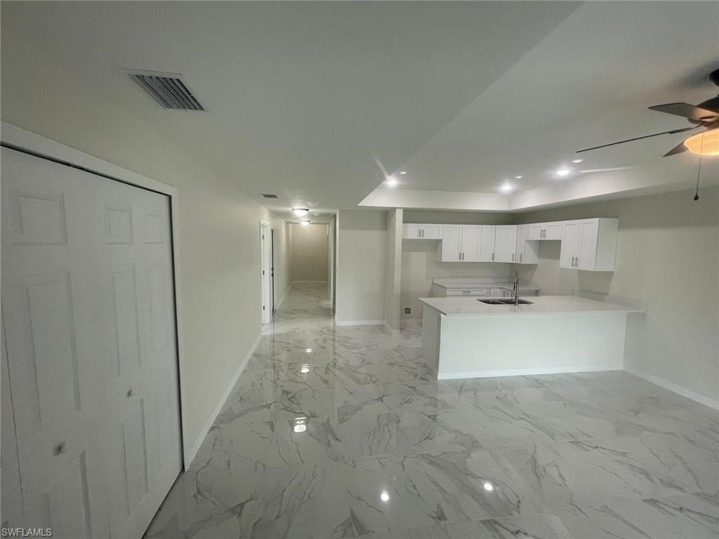 Kitchen with white cabinetry, kitchen peninsula, sink, and ceiling fan