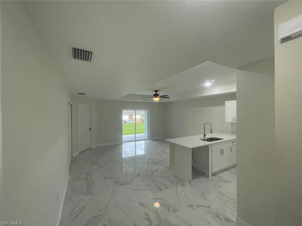 Kitchen featuring kitchen peninsula, sink, ceiling fan, and white cabinets