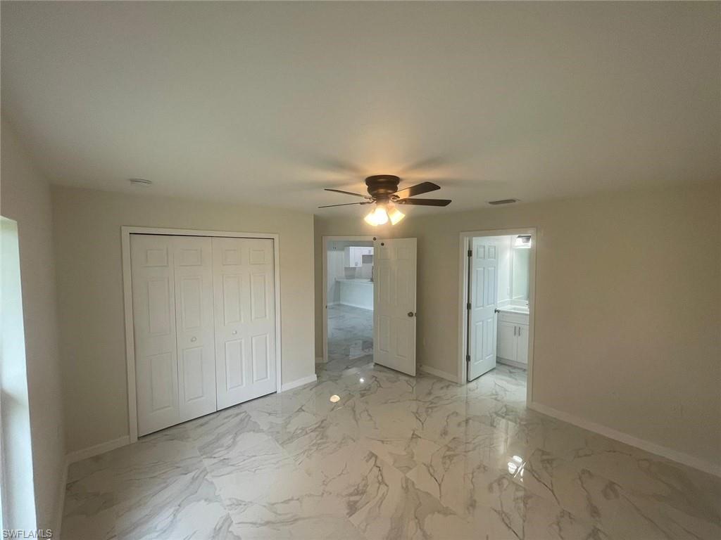 Unfurnished bedroom featuring ensuite bathroom, ceiling fan, and a closet