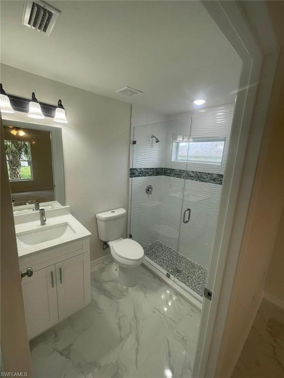 Bathroom with walk in shower, vanity, and toilet