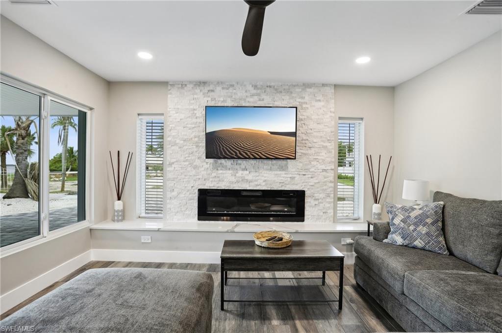 Living room with a stone fireplace, ceiling fan, and hardwood / wood-style floors
