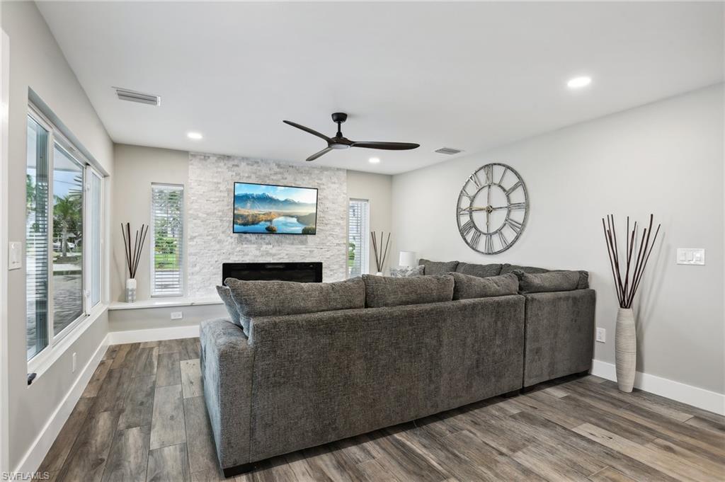 Living room featuring a fireplace, dark hardwood / wood-style flooring, and ceiling fan