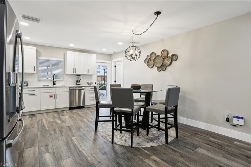 Dining space with sink, an inviting chandelier, and hardwood / wood-style floors