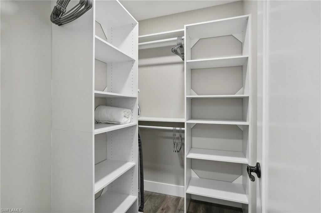 Spacious closet with dark hardwood / wood-style floors